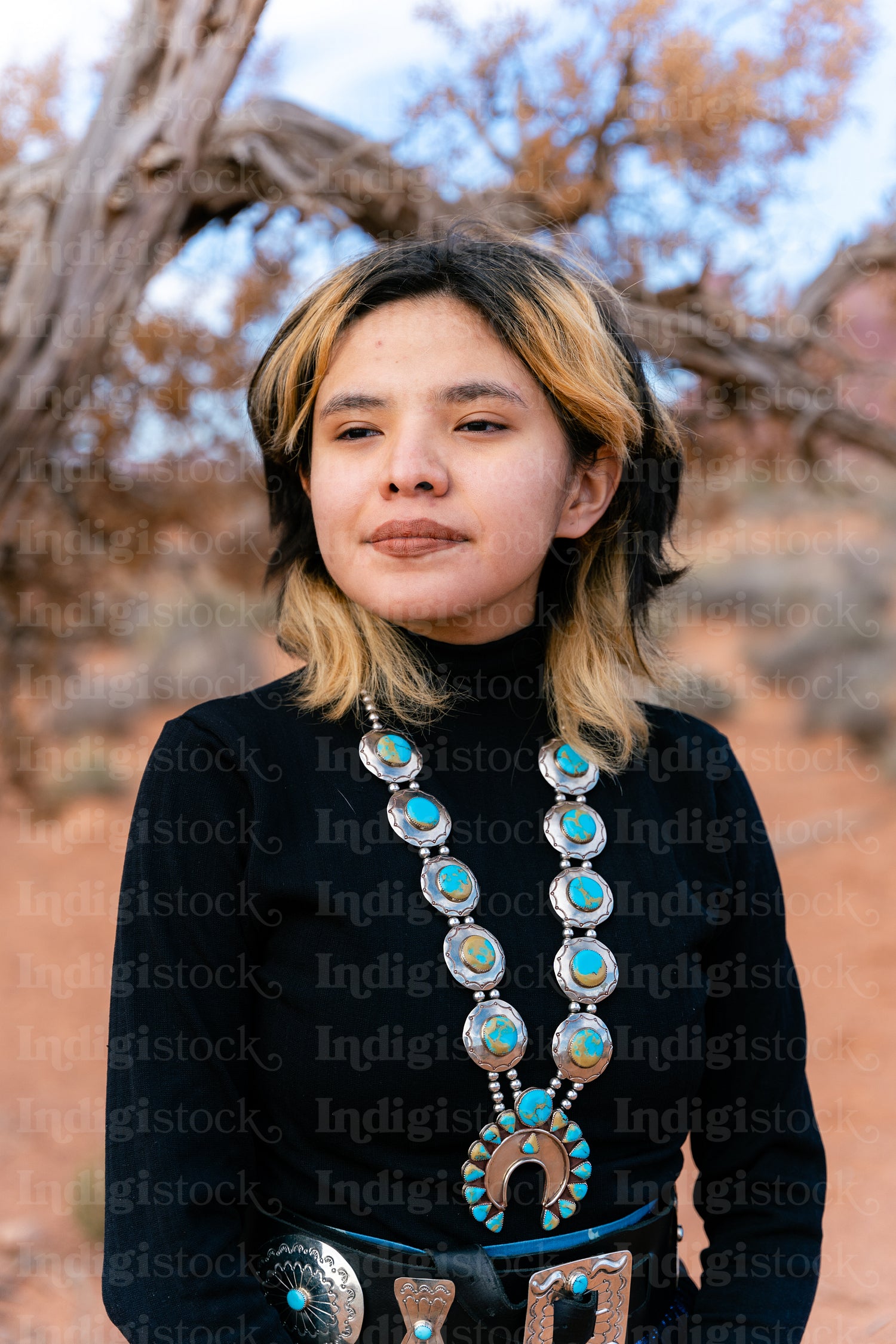 A young native teenager wearing traditional regalia outside