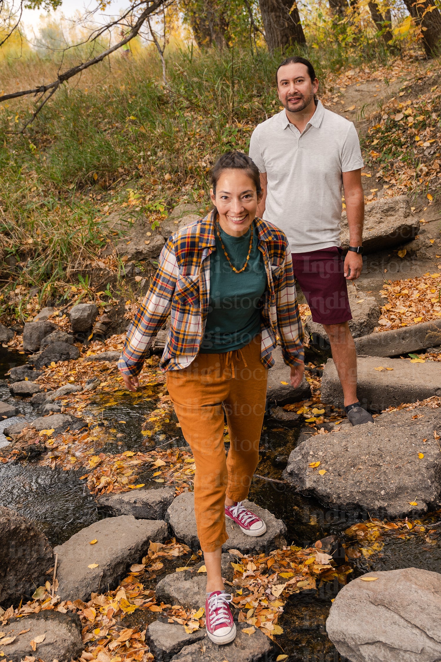 Native couple crossing a river in the woods