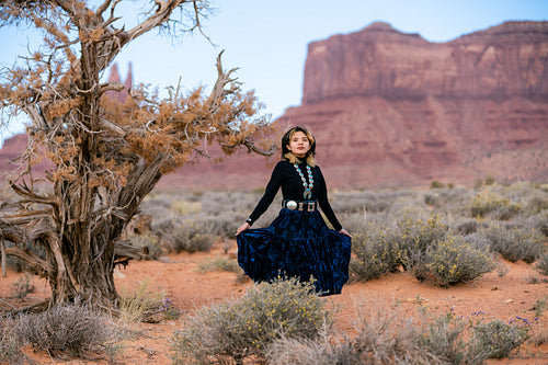 A young native teenager wearing traditional regalia outside