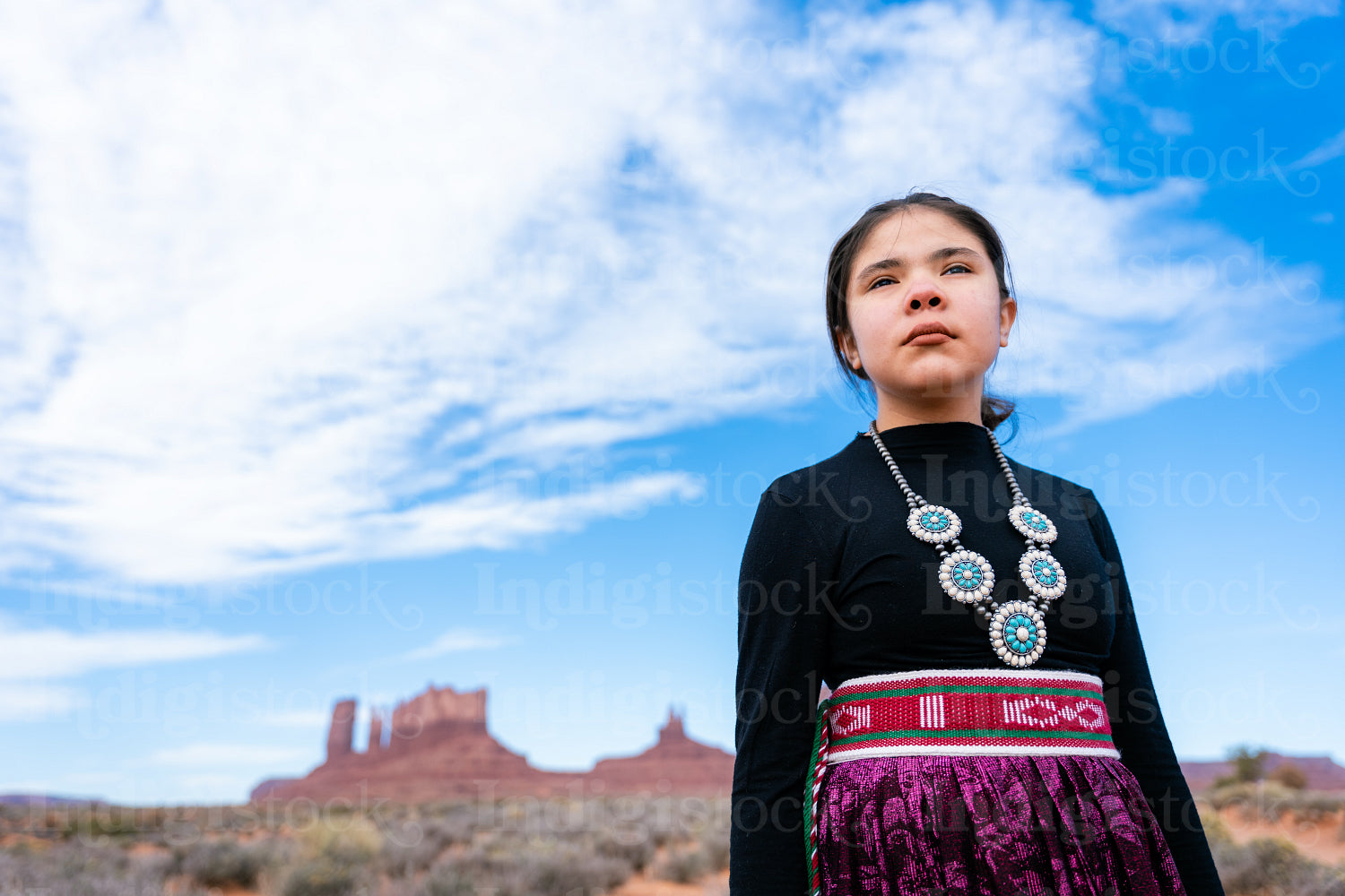 A young native teenager wearing traditional regalia outside