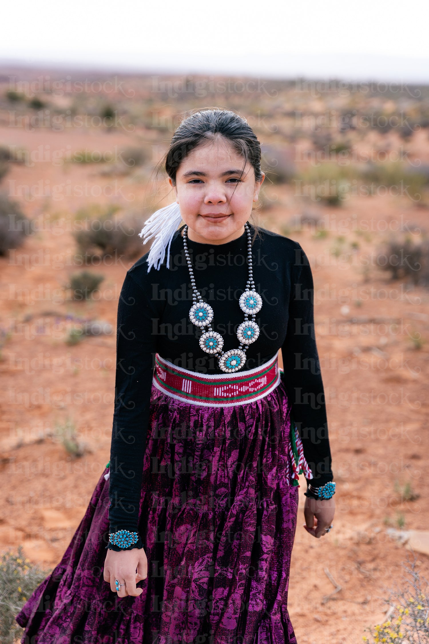 A young native teenager wearing traditional regalia outside