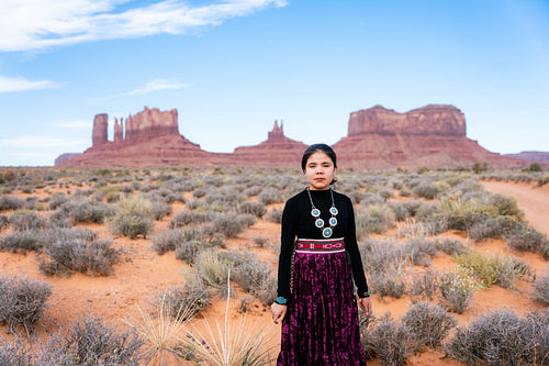 A young native teenager wearing traditional regalia outside