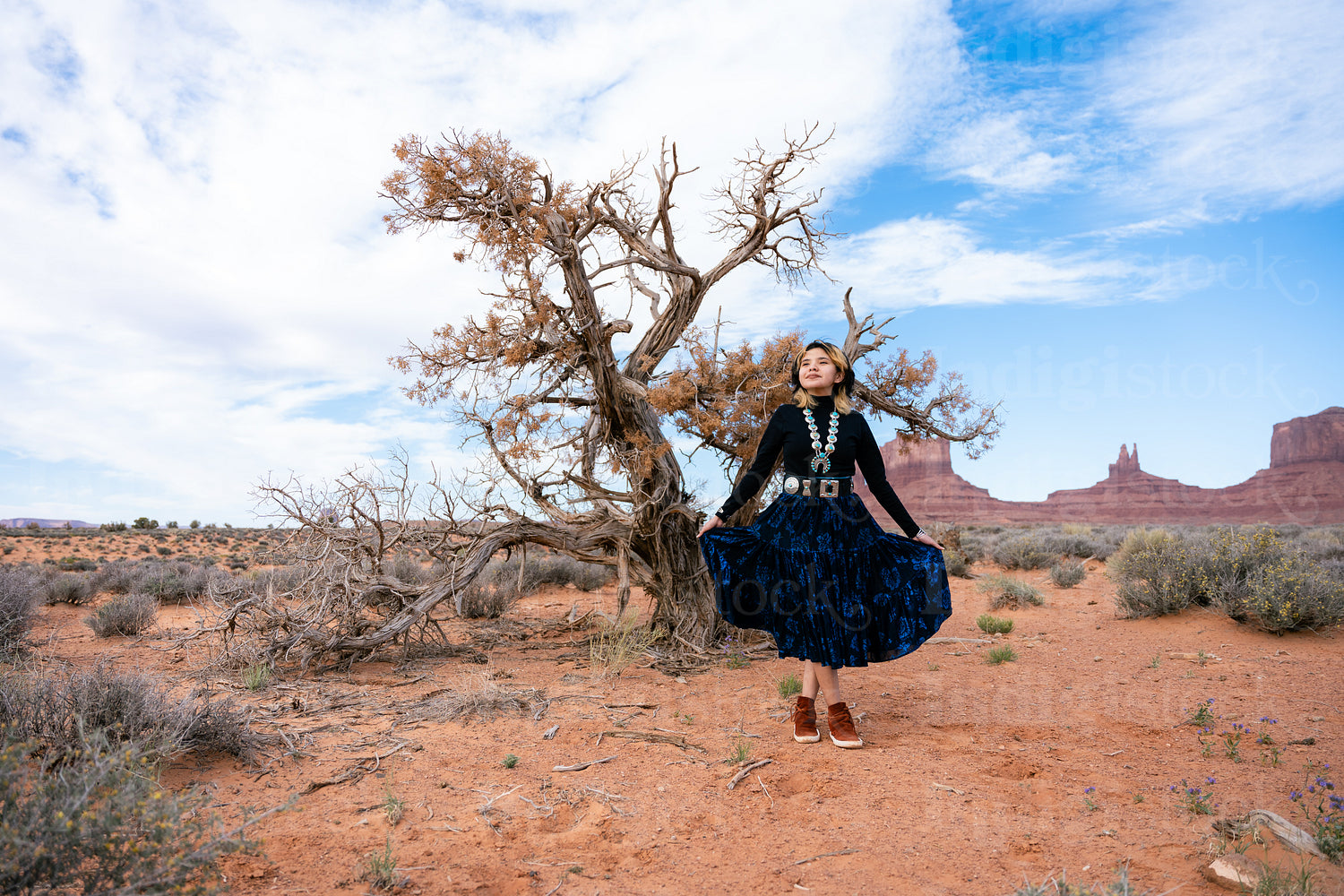 A young native teenager wearing traditional regalia outside