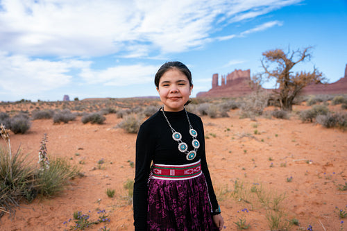 A young native teenager wearing traditional regalia outside