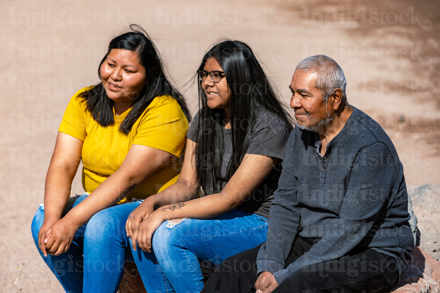 A Indigenous family sitting together by a lake