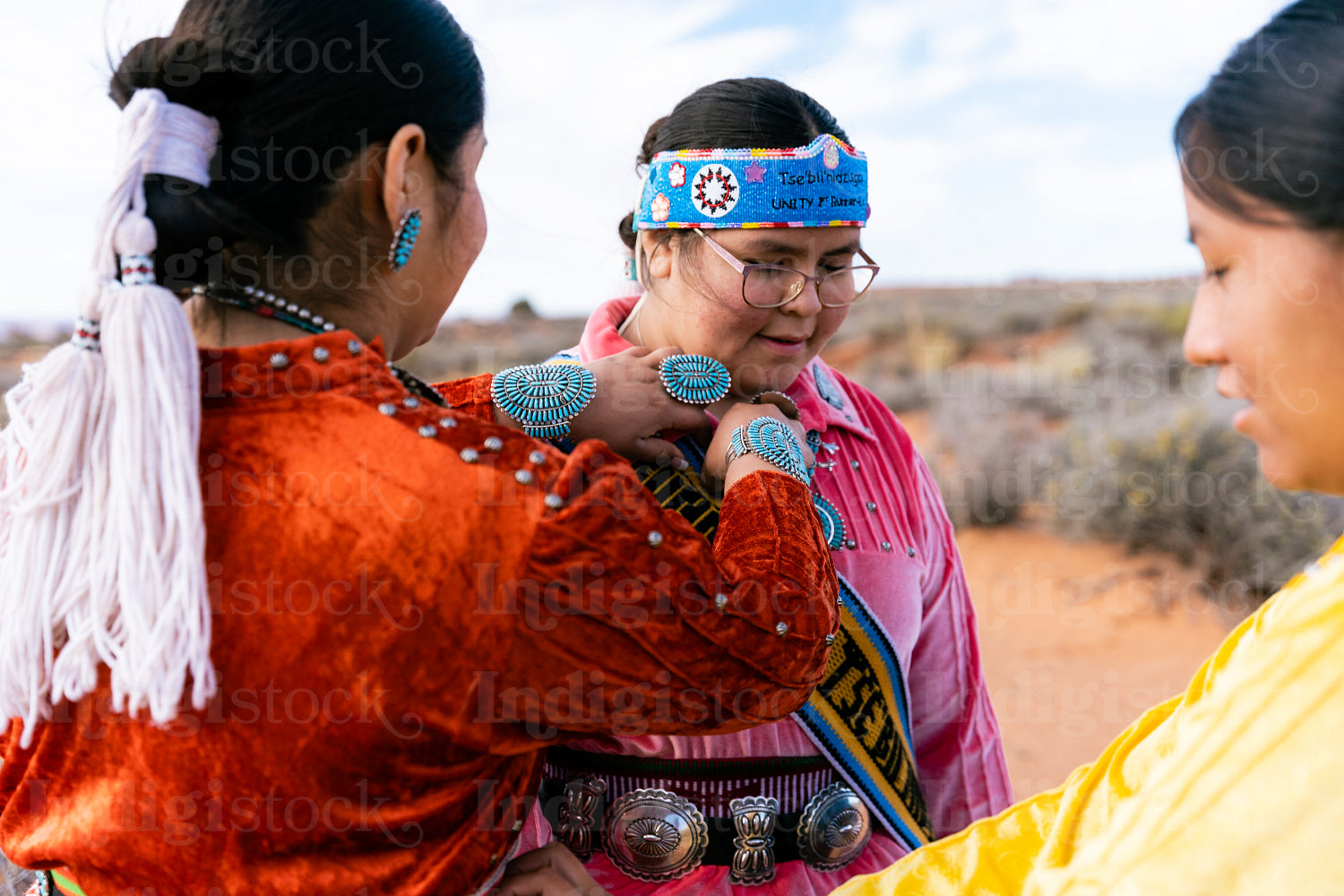 An indigenous family wearing traditional regalia outside