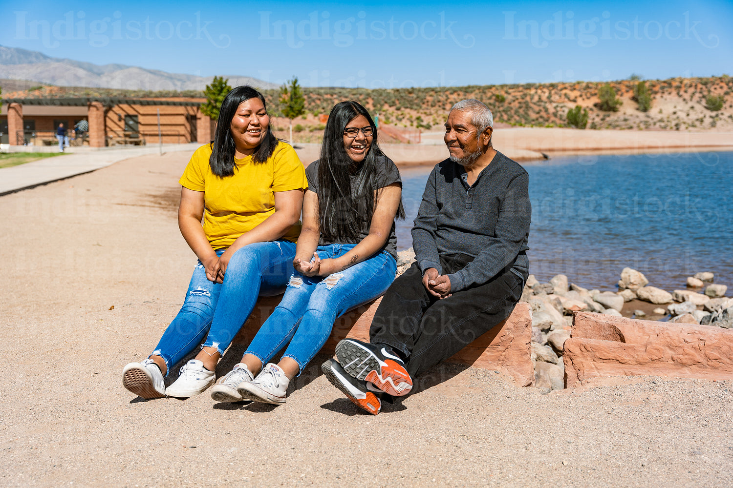 A Indigenous family sitting together by a lake