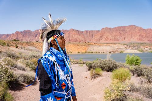 A Native Man wearing traditional regalia outside