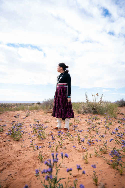 A young native teenager wearing traditional regalia outside