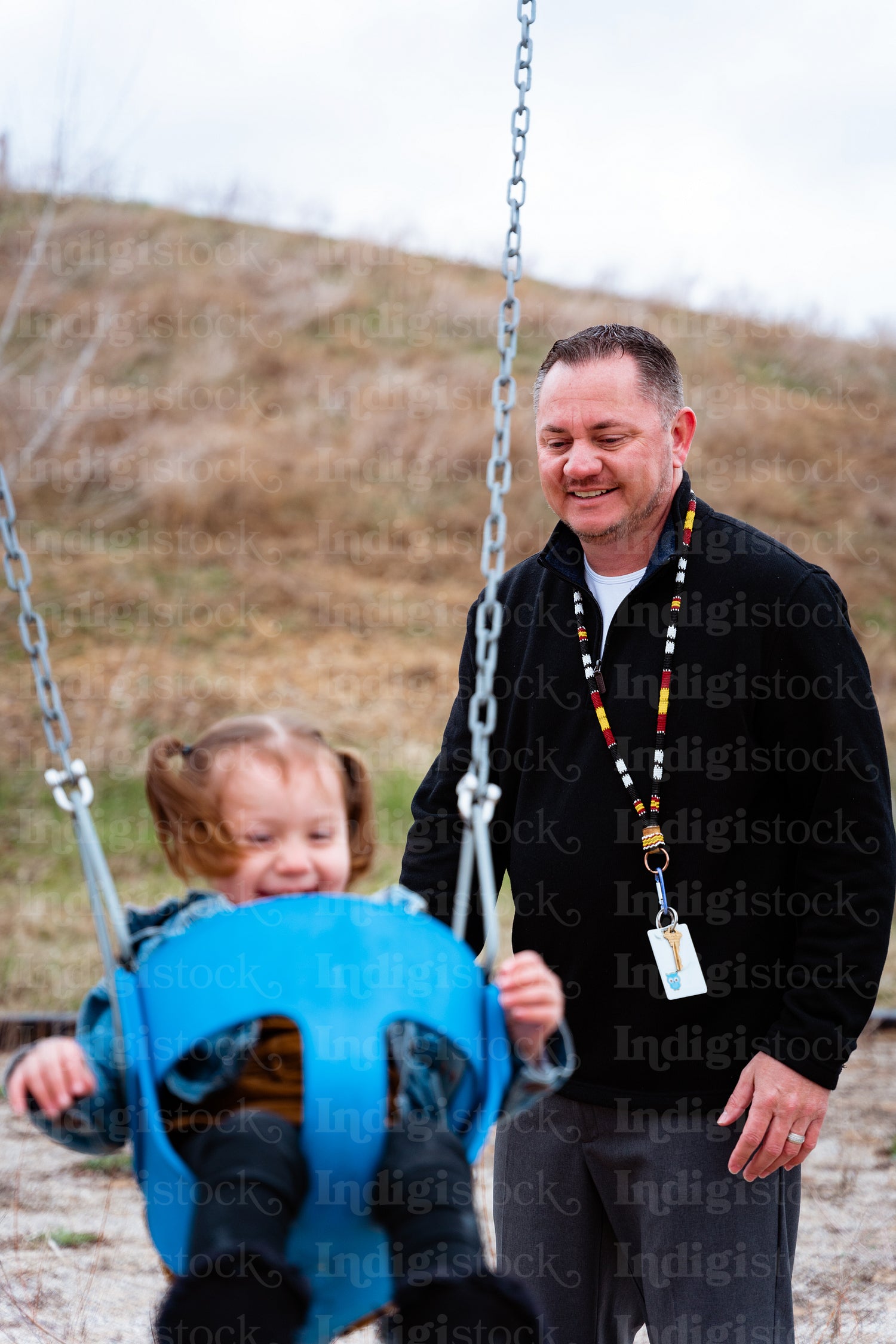 A father pushing his daughter on a swing