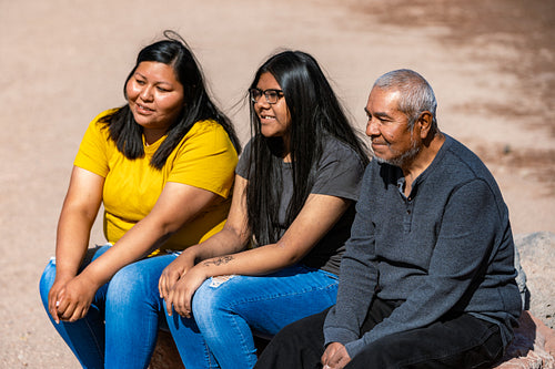 A Indigenous family sitting together by a lake