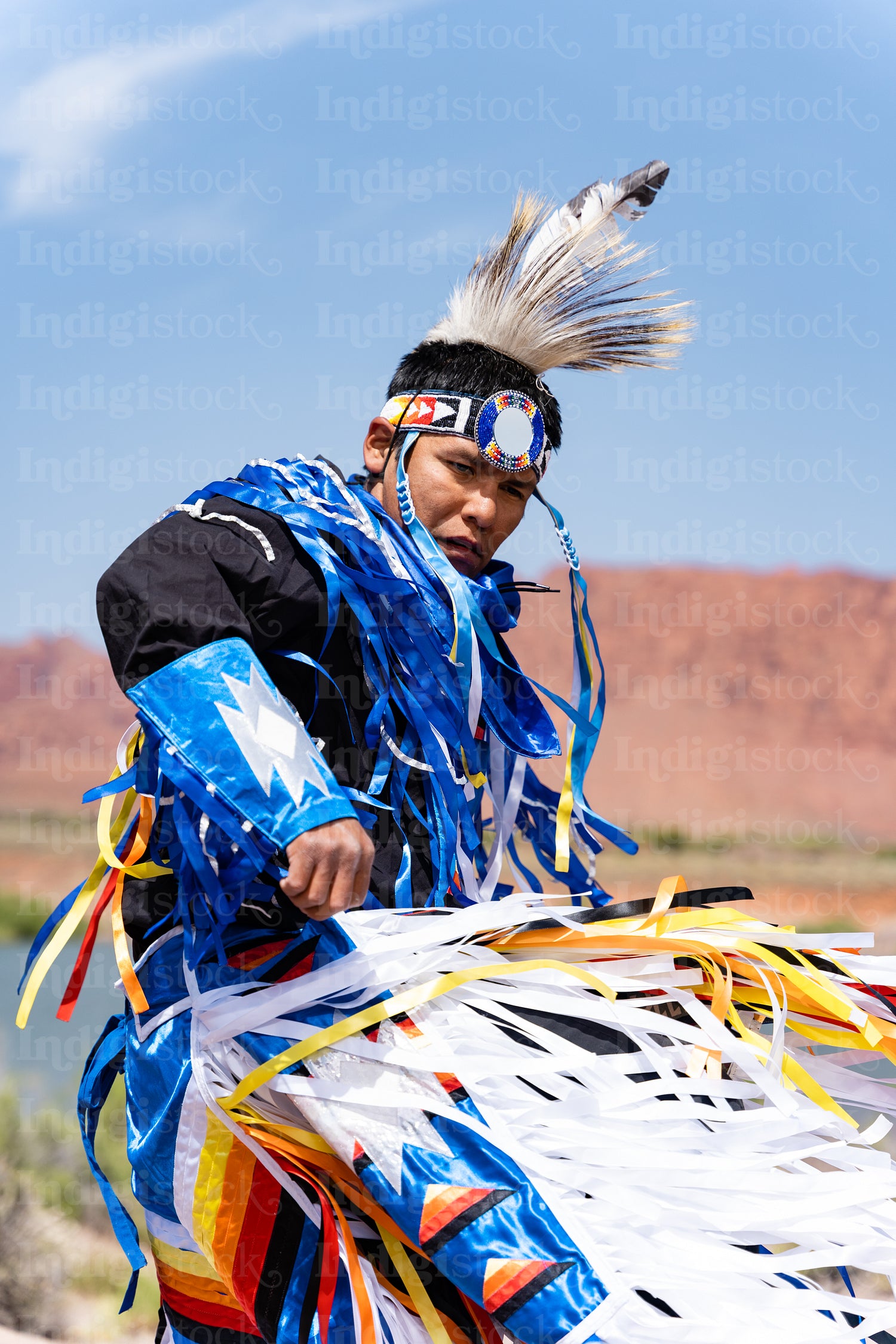 A Native Man wearing traditional regalia clothing outside