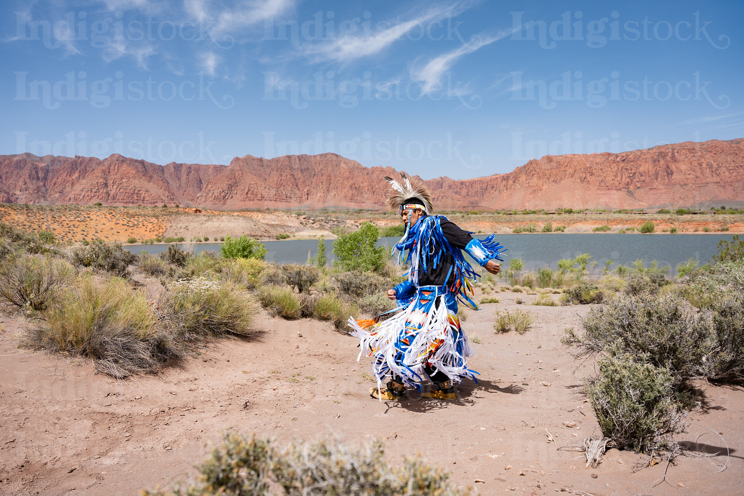 A Native Man wearing traditional regalia clothing outside