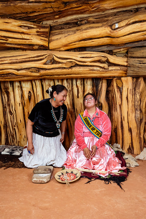 Two Navajo girls grinding corn into flour in Hogan Earthlodge