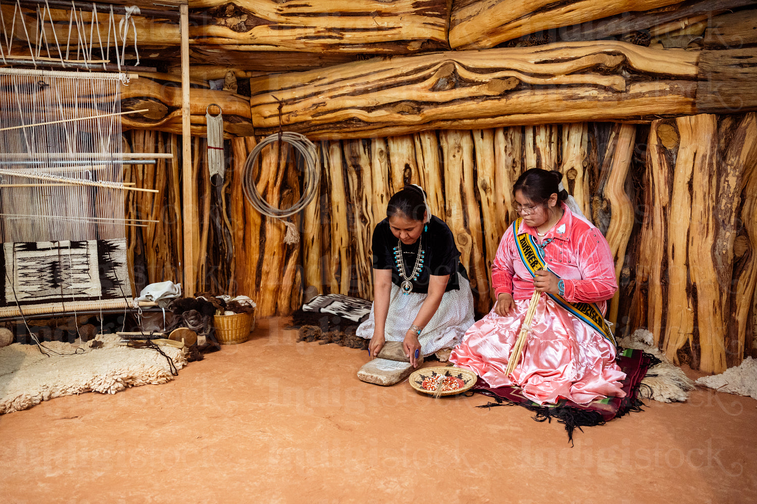 Two Navajo girls grinding corn into flour in Hogan Earthlodge 