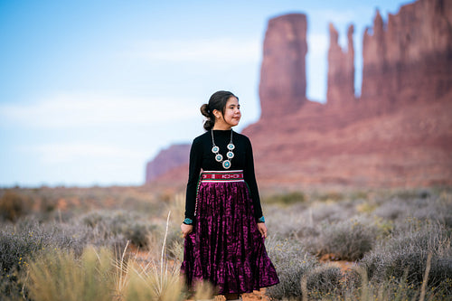 A young native teenager wearing traditional regalia outside