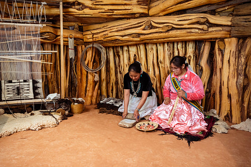 Two Navajo girls grinding corn into flour in Hogan Earthlodge