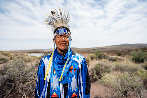 A Native Man wearing traditional regalia clothing outside