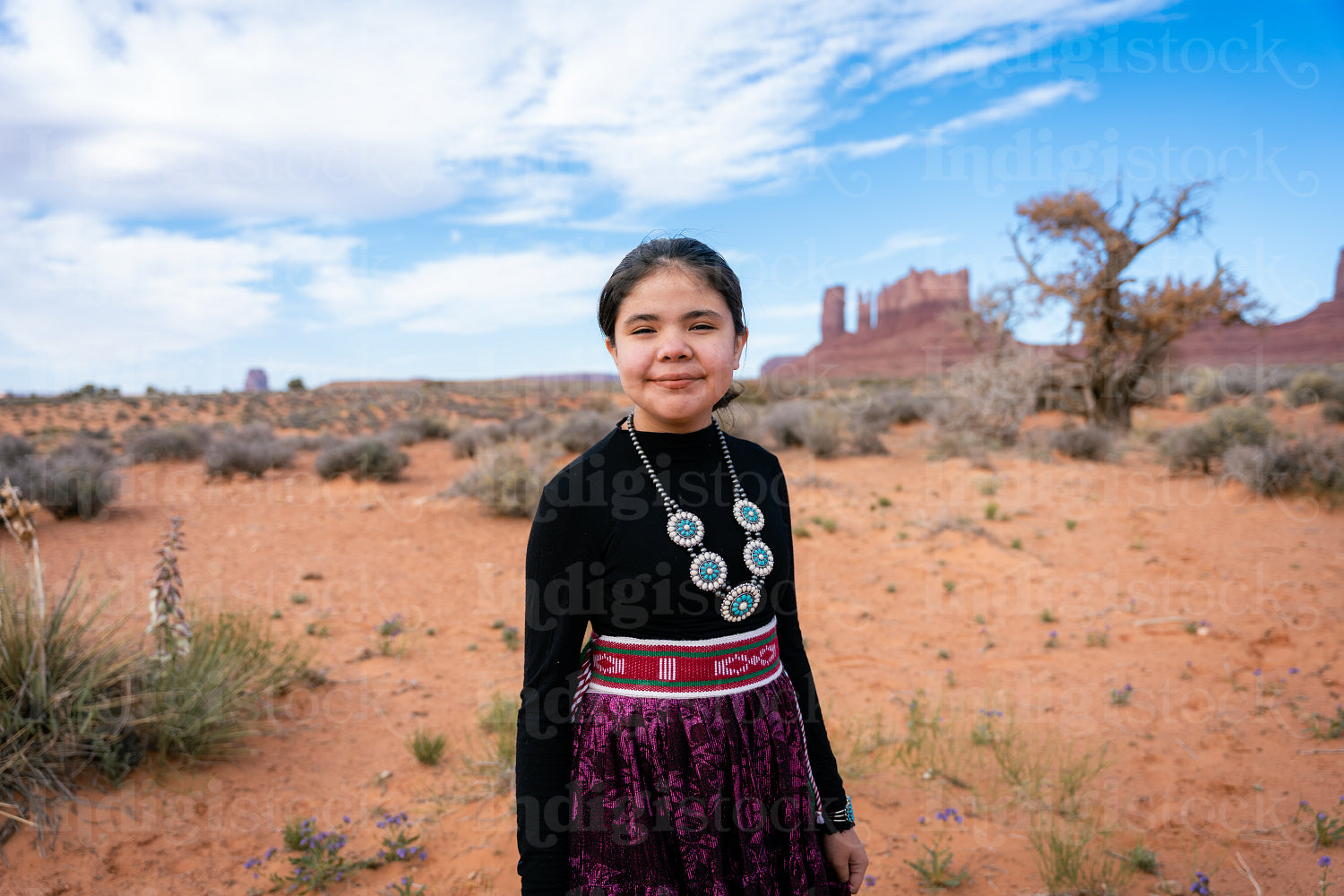 A young native teenager wearing traditional regalia outside