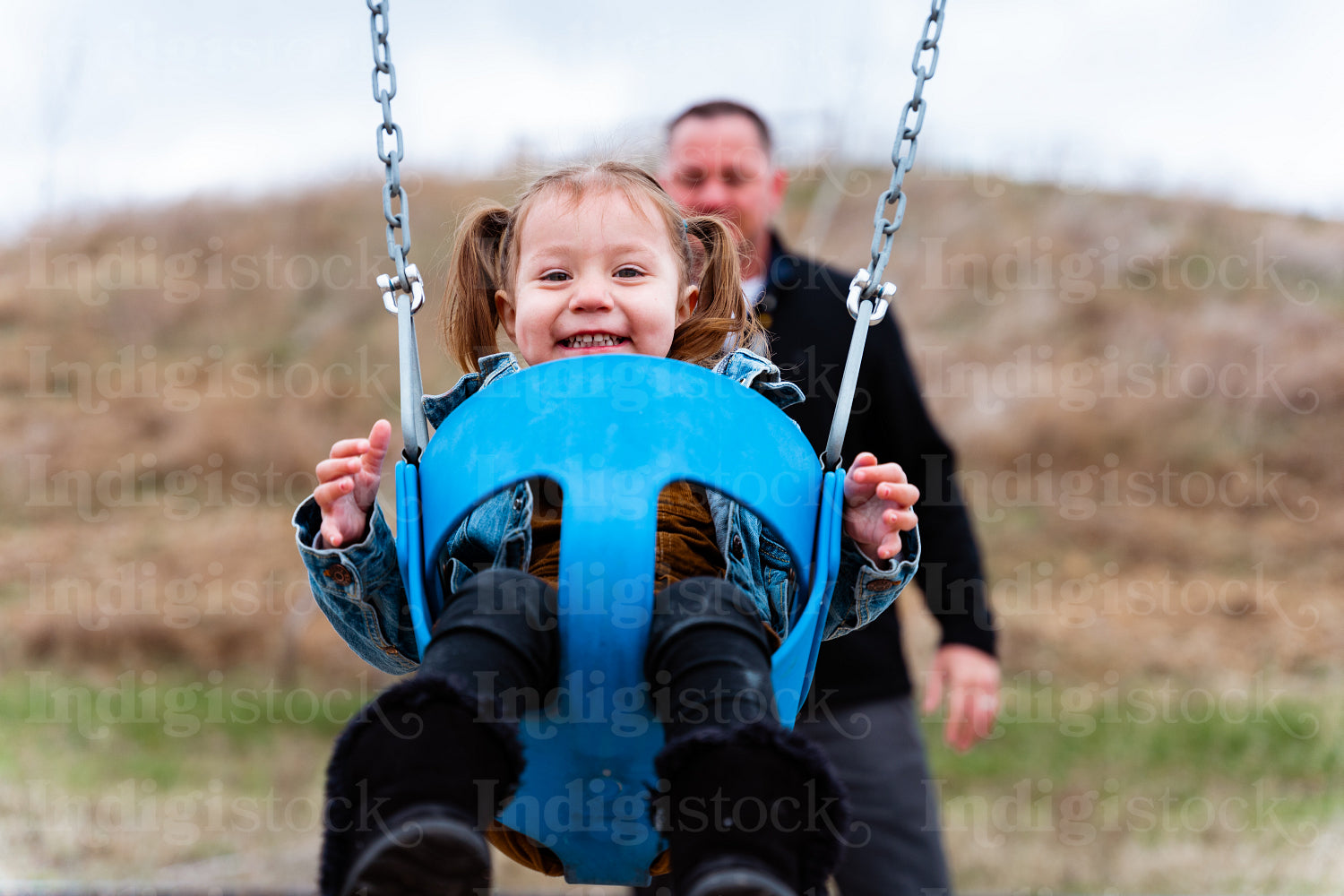 A father pushing his daughter on a swing