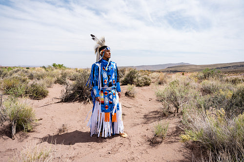 A Native Man wearing traditional regalia clothing outside