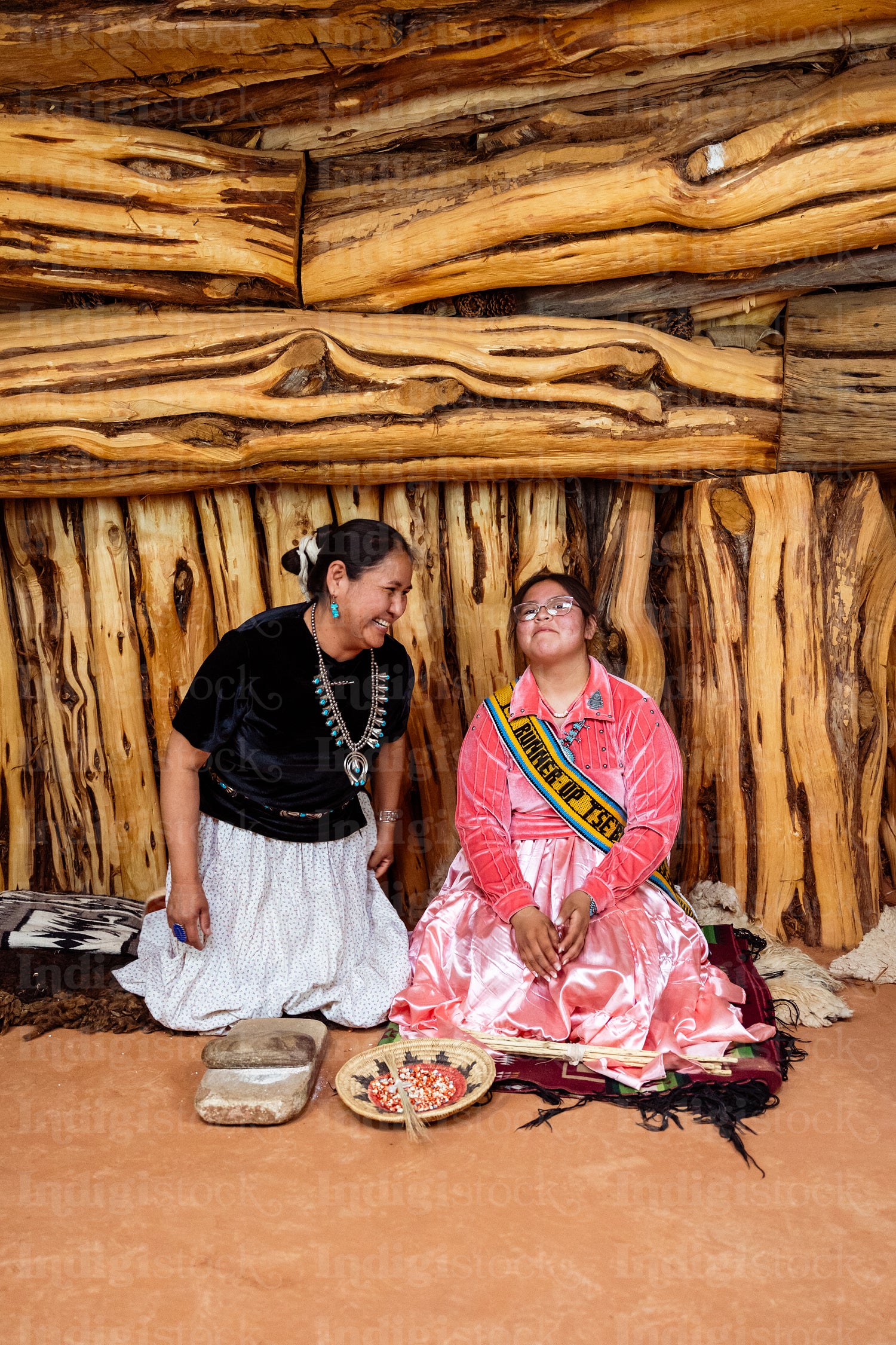 Two Navajo girls grinding corn into flour in Hogan Earthlodge 