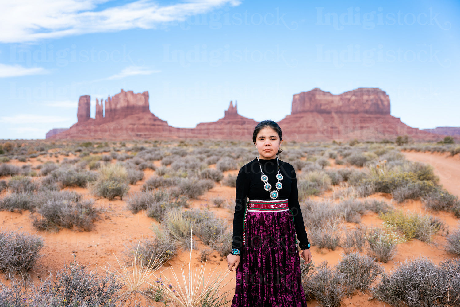 A young native teenager wearing traditional regalia outside