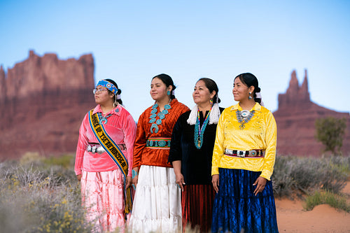 An indigenous family wearing traditional regalia outside