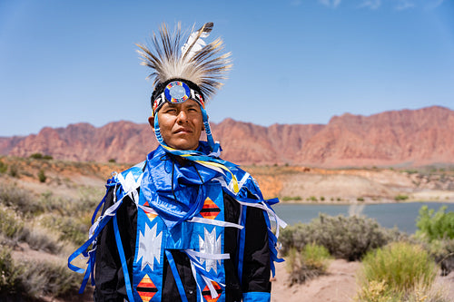 A Native Man wearing traditional regalia outside