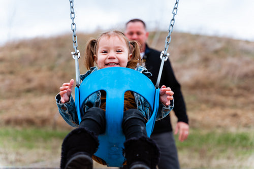 A father pushing his daughter on a swing