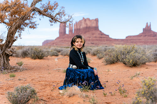 A young native teenager wearing traditional regalia outside