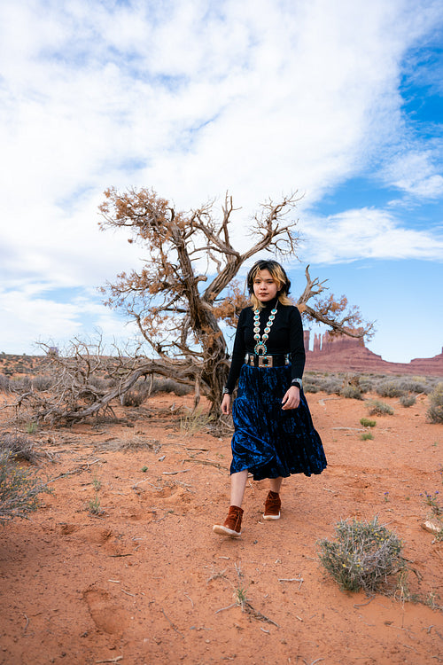 A young native teenager wearing traditional regalia outside