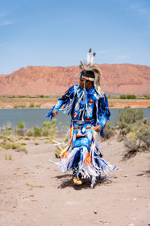 A Native Man wearing traditional regalia clothing outside