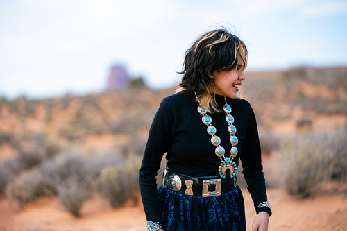 A young native teenager wearing traditional regalia outside