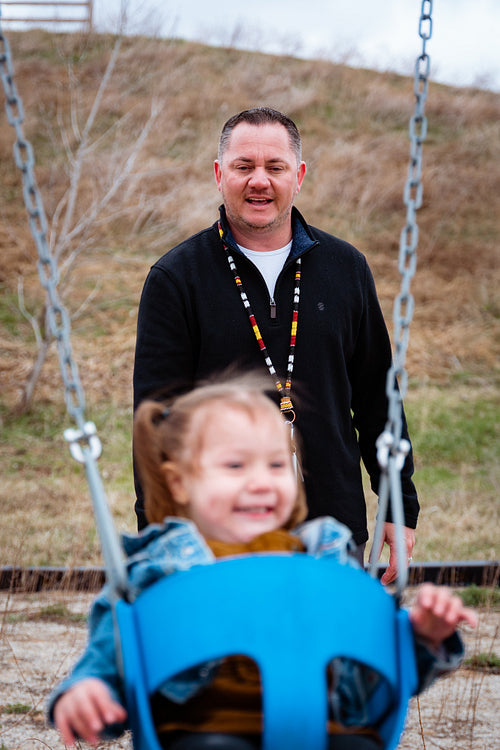 A father pushing his daughter on a swing