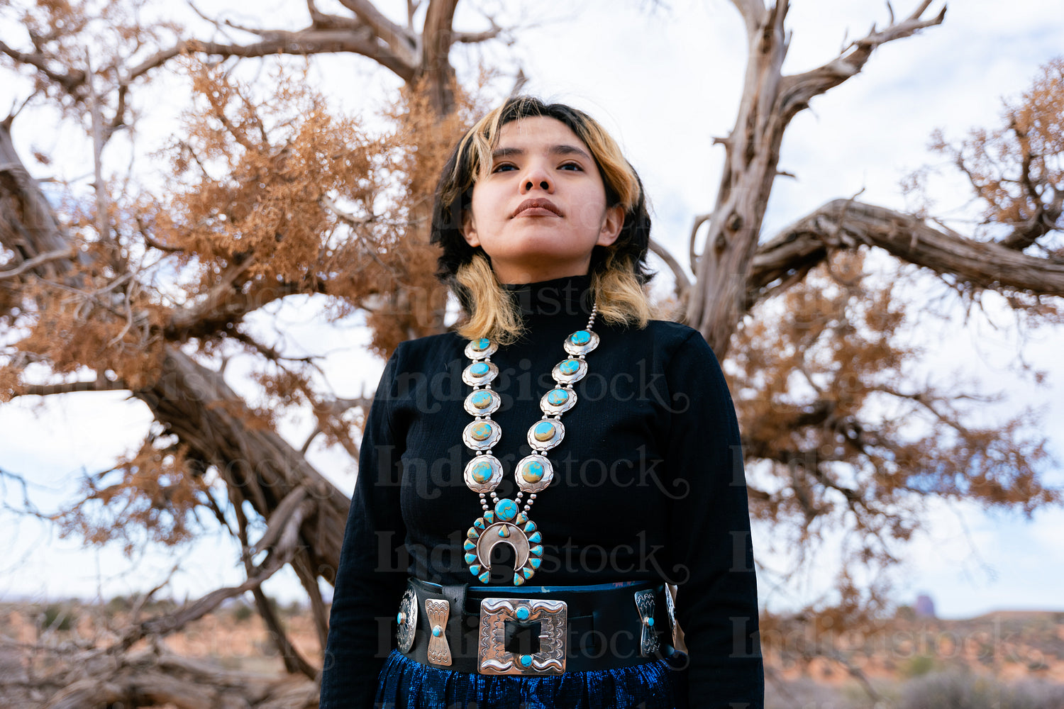 A young native teenager wearing traditional regalia outside