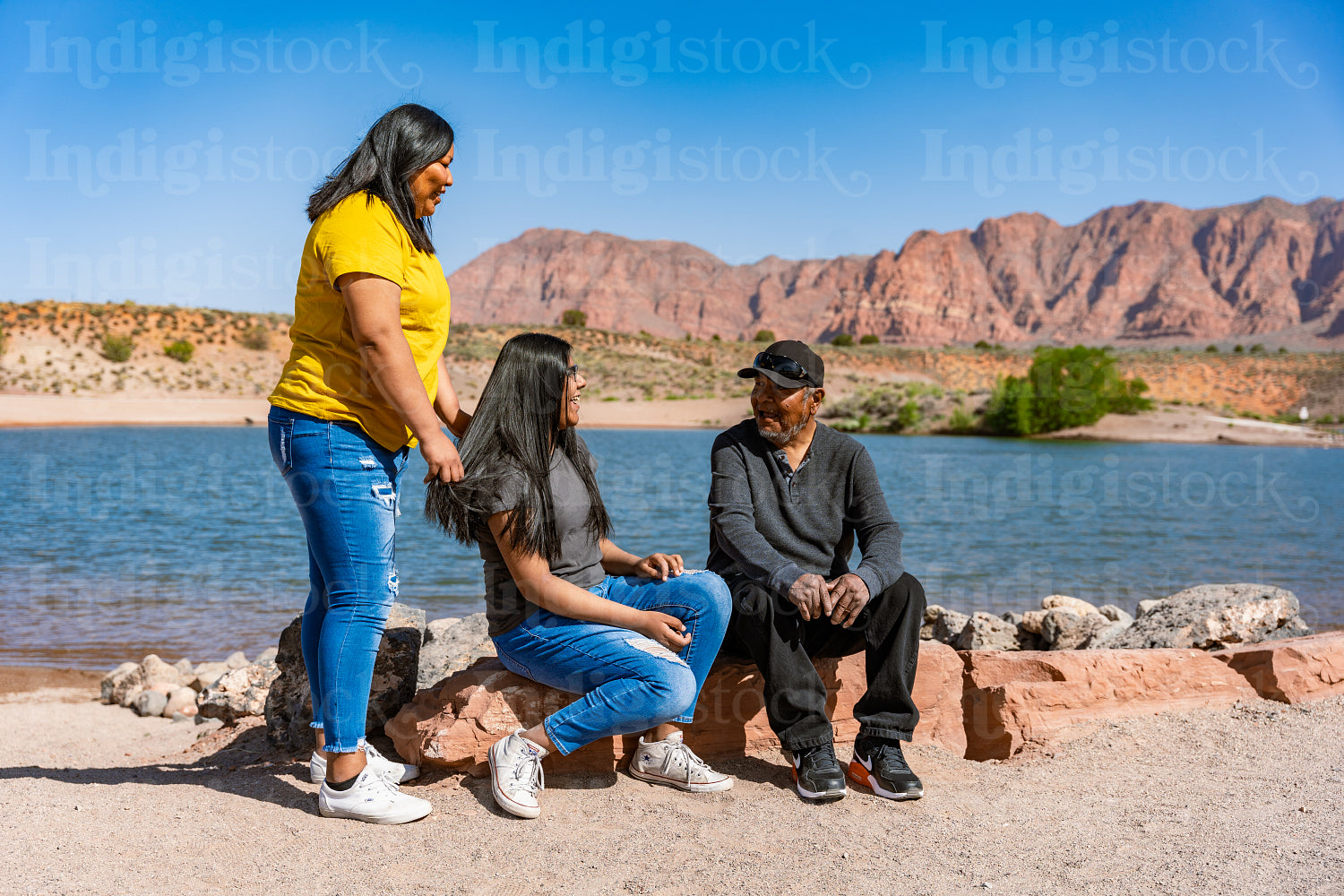 A Indigenous family sitting together by a lake