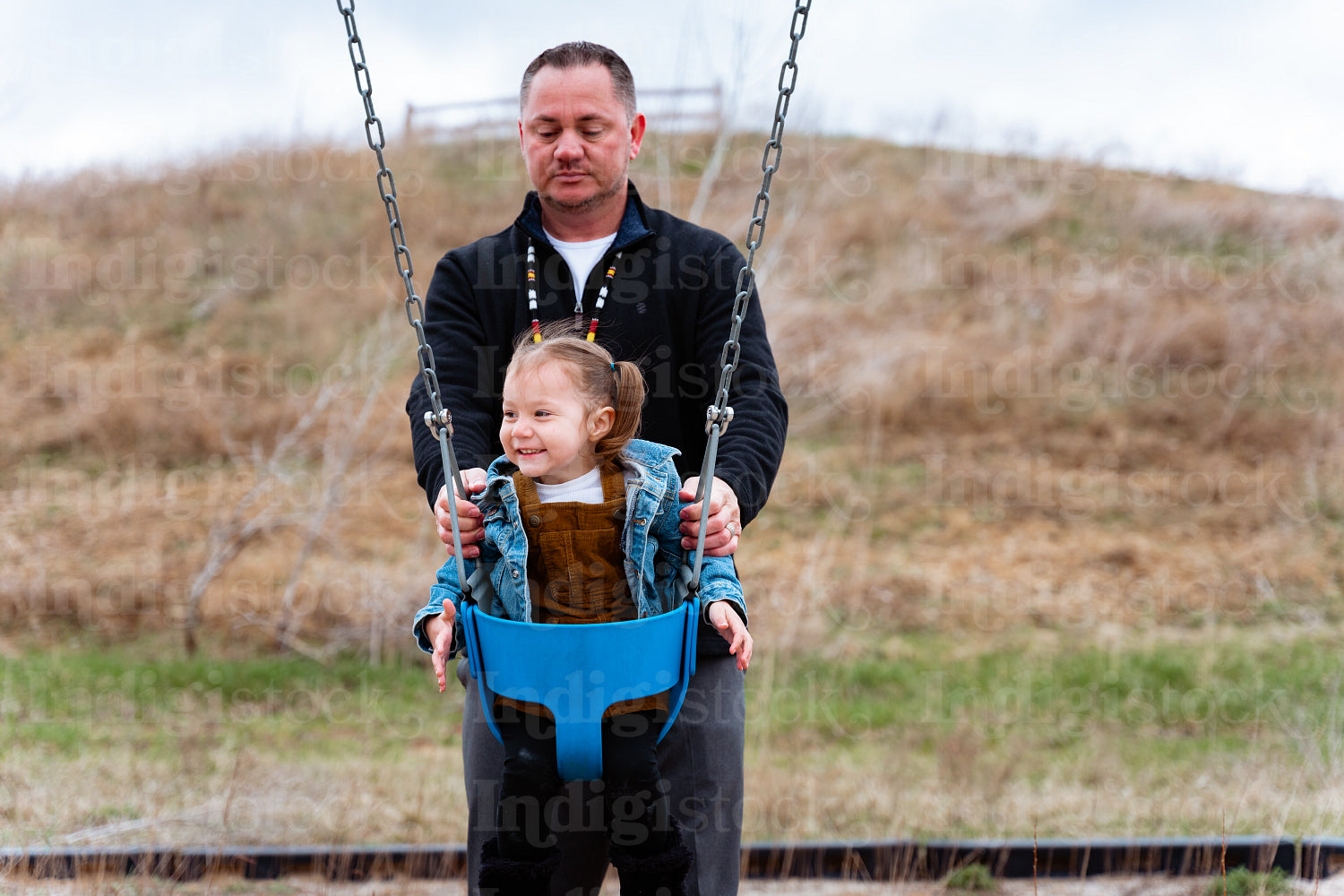 A father pushing his daughter on a swing