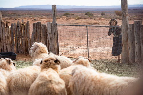 Young native youth wearing tradtional regalia looking at sheep