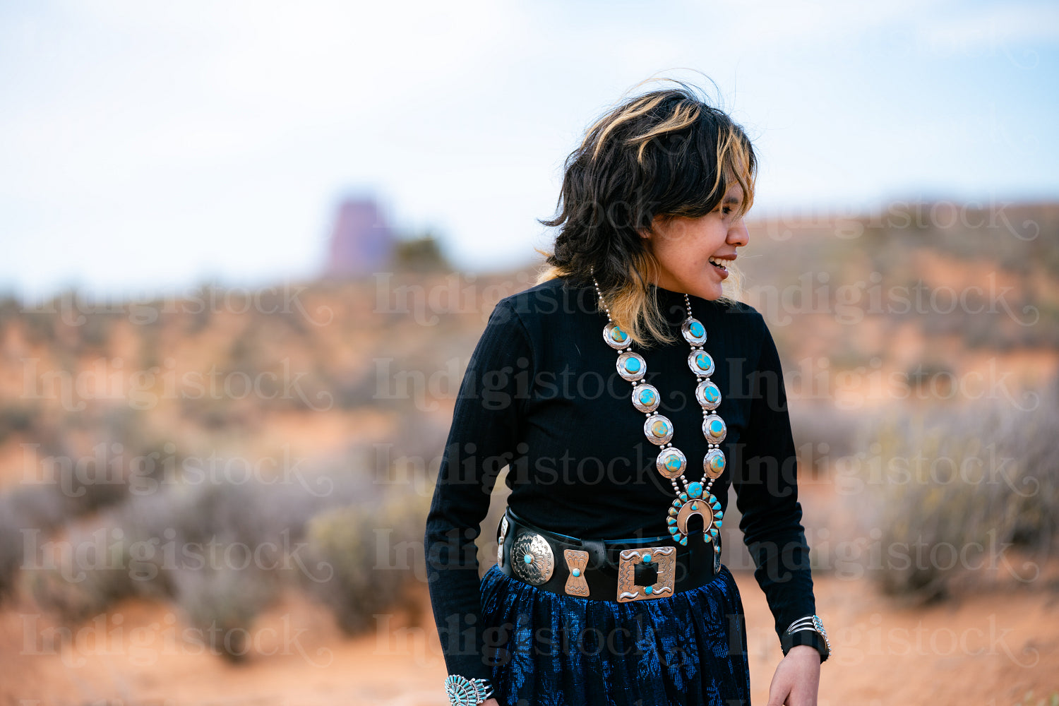 A young native teenager wearing traditional regalia outside