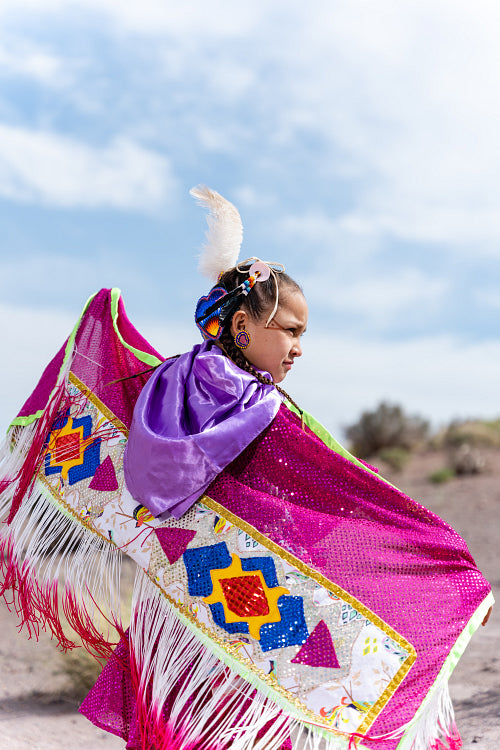 Young Native girl wearing traditional regalia outside