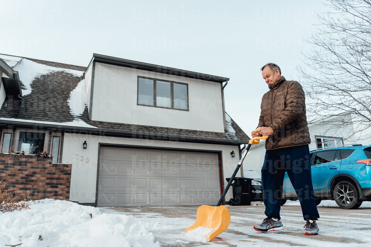 Indigenous man shoveling infront of his house