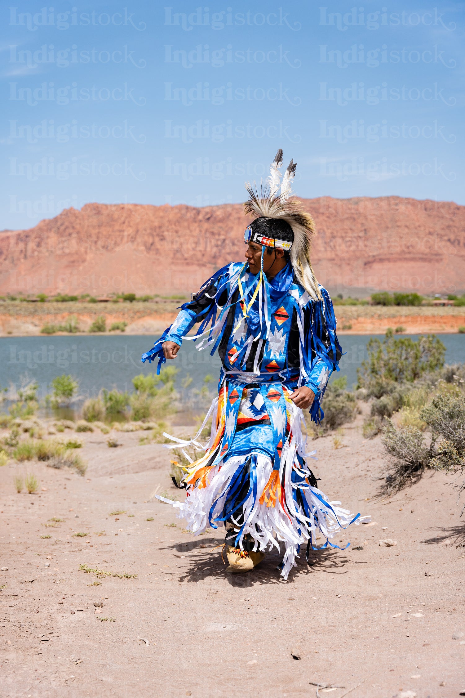 A Native Man wearing traditional regalia clothing outside