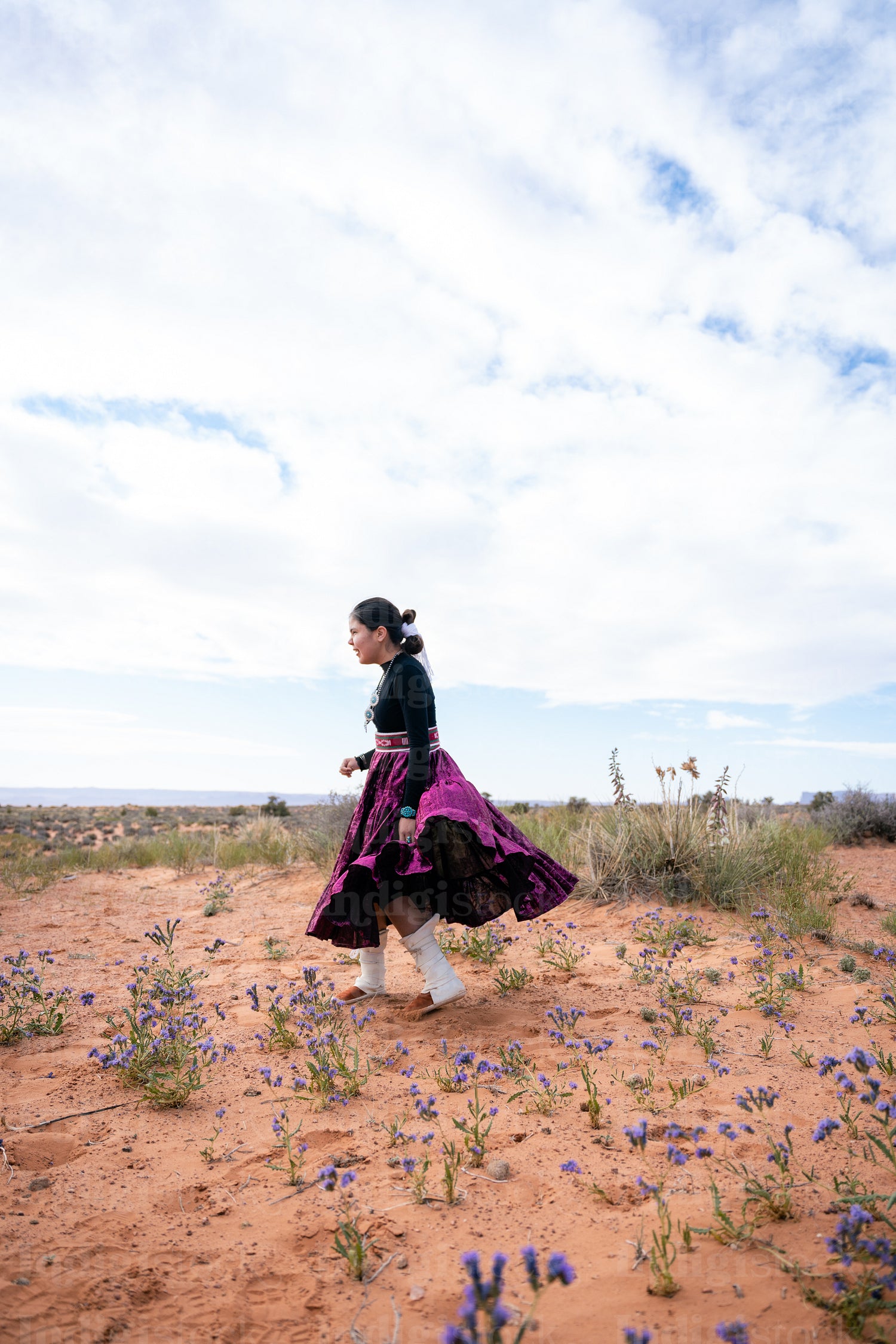 A young native teenager wearing traditional regalia outside